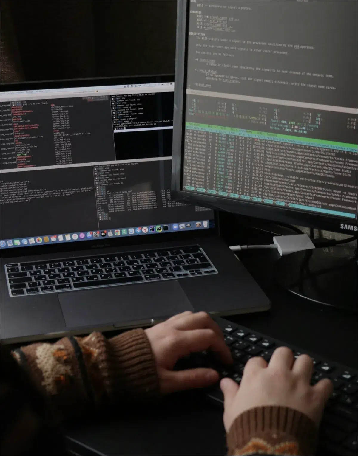 Hands of a software developer typing on a keyboard at a dual-monitor computer setup