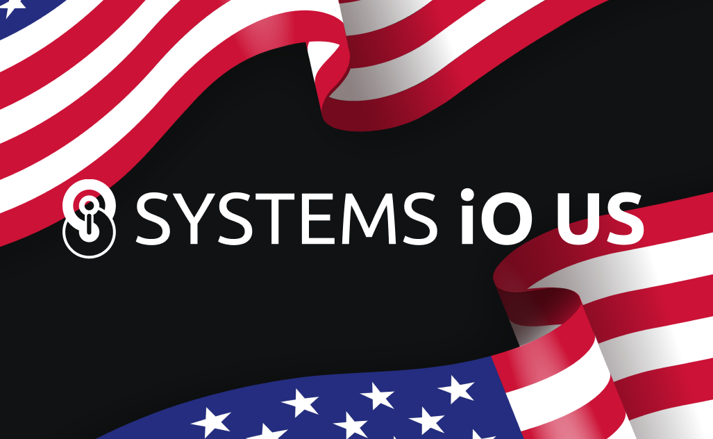 The 'Systems iO' logo with an added 'US' as a suffix in front of two waving American flags.
